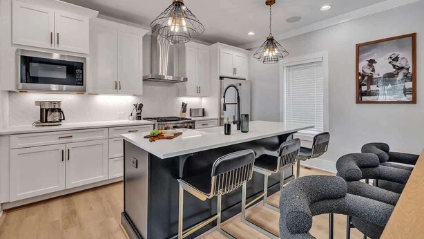 A modern kitchen with white cabinetry, stainless steel appliances, and a central island with bar stools. - Resonant - 2 Townhomes - 2 Private Rooftop Decks (Nashville)