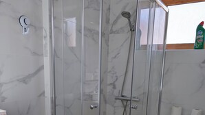 A bathroom with a glass-enclosed shower, a toilet, and a sink with a wooden cabinet. - Apartamento Santiago de la Ribera (San Javier)