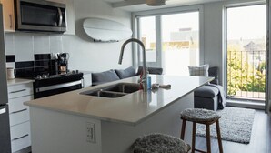 A modern kitchen with a central island, built-in microwave, and stainless steel appliances. - Trendy & Cozy Downtown Halifax Condo (Halifax)