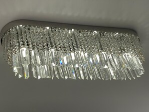A chandelier with multiple tiers of clear crystal elements. - The Luxury Holiday Home (Manchester)