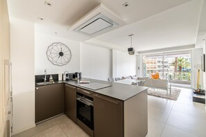 Una cucina moderna con isola centrale, forno integrato e un'ampia finestra che si affaccia su un balcone.