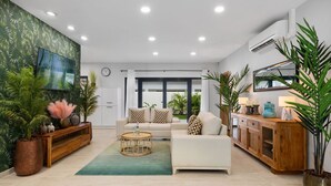Een moderne woonkamer met een bank, salontafel en potplanten.