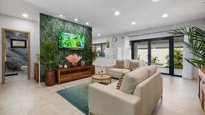 Een moderne woonkamer met een grote flatscreen televisie, een bank, een salontafel en een houten kast.