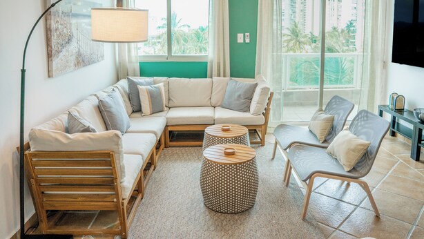 A living room with a sectional sofa, two side chairs, a coffee table, and a TV mounted on the wall.
