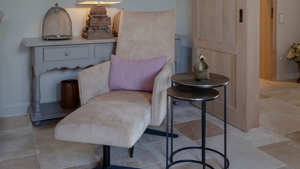 Une pièce confortable avec un fauteuil moelleux, une petite table et une lampe.