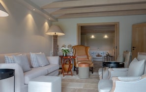 A living room with a sofa, armchairs, a lamp, and a wooden chair.