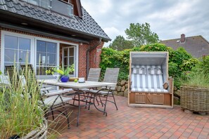 Une terrasse avec une table, des chaises et un espace salon abrité.