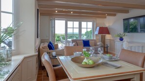 A dining area with a table set for four, a sofa, and a view of the outdoors. - Heefwai 2 - W1 - Holiday apartment "Heefwai 2 W1" in Morsum (Morsum)