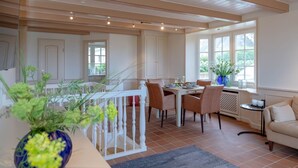 A dining area with a white table set for four, surrounded by chairs, and a sofa in the corner. - Heefwai 2 - W1 - Holiday apartment "Heefwai 2 W1" in Morsum (Morsum)