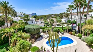 Una piscina circondata da palme e cactus, con edifici sullo sfondo.