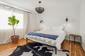 A bedroom with a bed, a potted plant, a cowhide rug, a small stool, and a hanging light fixture. - LAZY H BAR RANCH ESTATE, 3 /2,  AC, Pool, Hot Tub, BBQ, Horses and Dogs Welcome! (Tucson)
