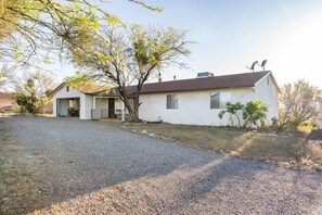 A single-story house with a gravel driveway, a garage, and a tree in front. - LAZY H BAR RANCH ESTATE, 3 /2,  AC, Pool, Hot Tub, BBQ, Horses and Dogs Welcome! (Tucson)