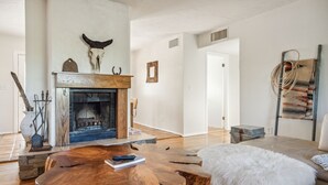 Ein geräumiges Wohnzimmer mit Kamin, Couchtisch aus Holz und einer Sitzecke.