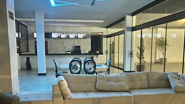 A modern living room with a glass coffee table, beige sofas, and a unique ceiling light fixture. - Jbr park hotel (Goiania)