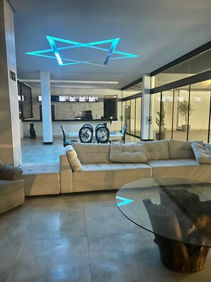 A modern living room with a glass coffee table, beige sofas, and a unique ceiling light fixture. - Jbr park hotel (Goiania)
