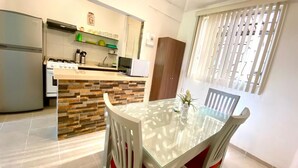 A modern kitchen with a built-in island, a dining table with chairs, and a window with blinds.