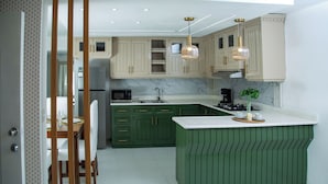 A kitchen with green cabinets, white countertops, and a marble backsplash. - Costa del sol (Sosúa)
