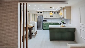 A modern kitchen with green cabinets, a stainless steel refrigerator, and a dining area with a wooden table and chairs. - Costa del sol (Sosúa)