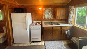 Una cocina compacta con refrigerador, estufa, lavaplatos y armarios de madera.