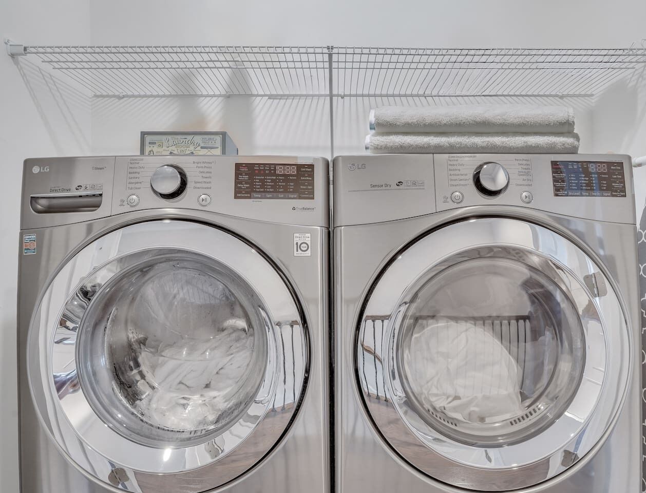 A pair of stainless steel LG Direct Drive front-loading washing machines with a control panel and a sensor dry feature.