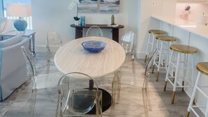 Una cuina moderna amb taula rodona, caires transparents i zona de bar amb tamborets.