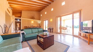 Un amplio salón con un sofá verde, una mesa de centro de madera y un televisor sobre un mueble de madera.