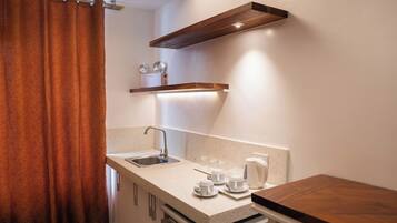 Una cocina moderna con encimera, lavabo y estante de madera arriba.