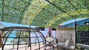 A covered outdoor area with a circular seating arrangement, a hanging chair, and a sofa. - The Paragon Boracay Suites (Boracay Island)