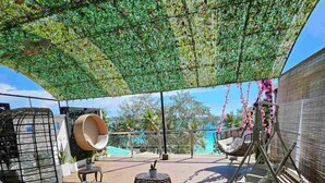 An outdoor patio area with a cushioned seating arrangement, a hanging chair, and a large planter. - The Paragon Boracay Suites (Boracay Island)