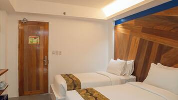 A hotel room with two beds, a wooden door, and a blue accent wall.