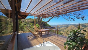 A wooden deck with a hot tub, chairs, and a table, overlooking a mountainous landscape. - El Sol Monteverde (Monteverde)