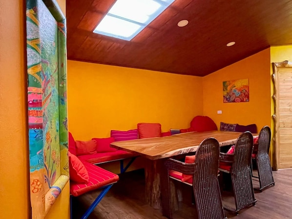 Un comedor acogedor con mesa y sillas de madera, paredes de color naranja intenso y un tragaluz.