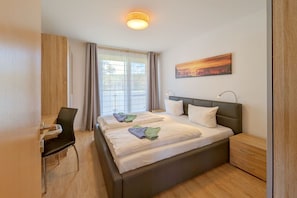 Ein Hotelzimmer mit Bett, Schreibtisch, Stuhl, Nachttisch und einem Bild an der Wand.