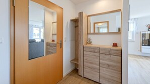 A hallway with a wooden door, a mirrored wardrobe, and a small shelf with decorative items. - "Spacious vacation apartment in Ückeritz for up to 4 people - 68m²" - (Ückeritz)