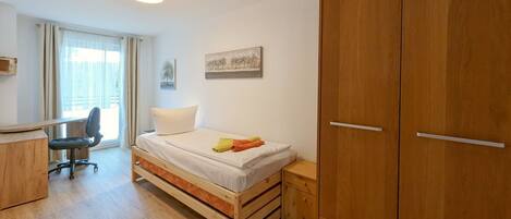 A bedroom with a bed, a desk, a chair, and a wardrobe.