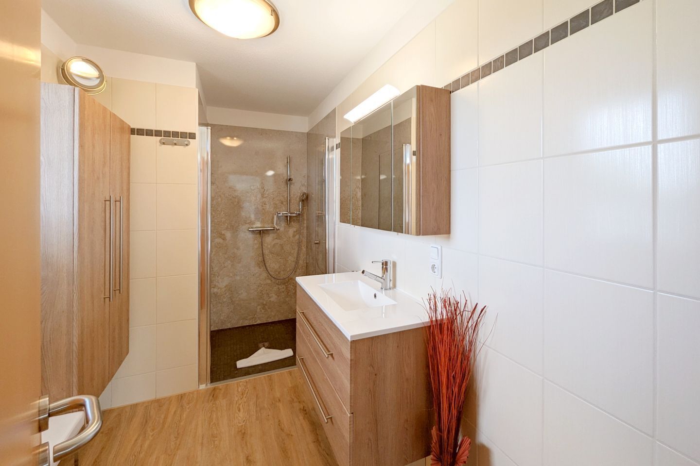 A modern bathroom with a shower, a sink, and a mirror.