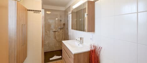 A modern bathroom with a shower, a sink, and a mirror.