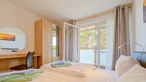A hotel room with two beds, a desk, a chair, and a balcony with curtains. - "Spacious vacation apartment in Ückeritz for up to 4 people - 68m²" - (Ückeritz)