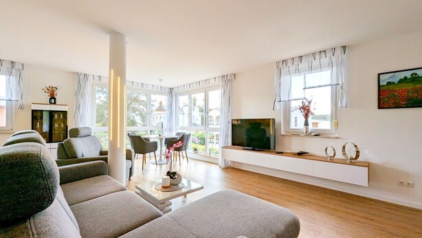 A modern living room with a sofa, a coffee table, a TV, and a dining area with chairs. - "Spacious vacation apartment in Ückeritz for up to 4 people - 68m²" - (Ückeritz)