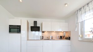 A modern kitchen with white cabinetry, a built-in oven, a microwave, a coffee maker, and a toaster. - "Spacious vacation apartment in Ückeritz for up to 4 people - 68m²" - (Ückeritz)
