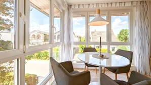A dining area with a round table and four chairs, large windows with curtains, and a hanging pendant light. - "Spacious vacation apartment in Ückeritz for up to 4 people - 68m²" - (Ückeritz)