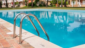 A swimming pool with metal ladders, surrounded by a tiled deck and buildings in the background. - GuestReady - A paradisíac stay in Fão (Esposende)