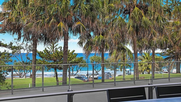 An outdoor seating area with a view of the ocean and parked cars. - Spinnaker Apt 6- Mooloolaba Beach  (Mooloolaba)
