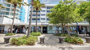 A modern hotel with a Spinnaker sign, palm trees, and a sidewalk with planters. - Spinnaker Apt 6- Mooloolaba Beach  (Mooloolaba)