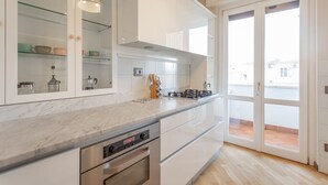 A modern kitchen with white cabinets, a marble countertop, and a built-in oven. - Monteverde 2BDR  Penthouse (Roma)