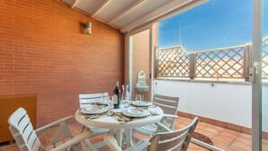 A patio with a round table set for dining, white chairs, and a bottle of wine. - Monteverde 2BDR  Penthouse (Roma)