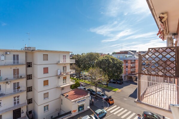 A multi-story building with balconies, a street view, and a clear sky.