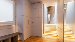 A modern interior with a wooden floor, a bench, and a staircase with illuminated steps. - Spanish Steps Rooftop Penthouse (Roma)