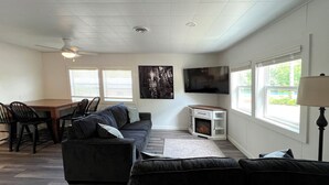 Una sala de estar con sofá, televisor, chimenea y un comedor con sillas y mesa.
