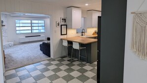 A modern kitchen with a checkered floor, a bar area, and a window providing natural light.